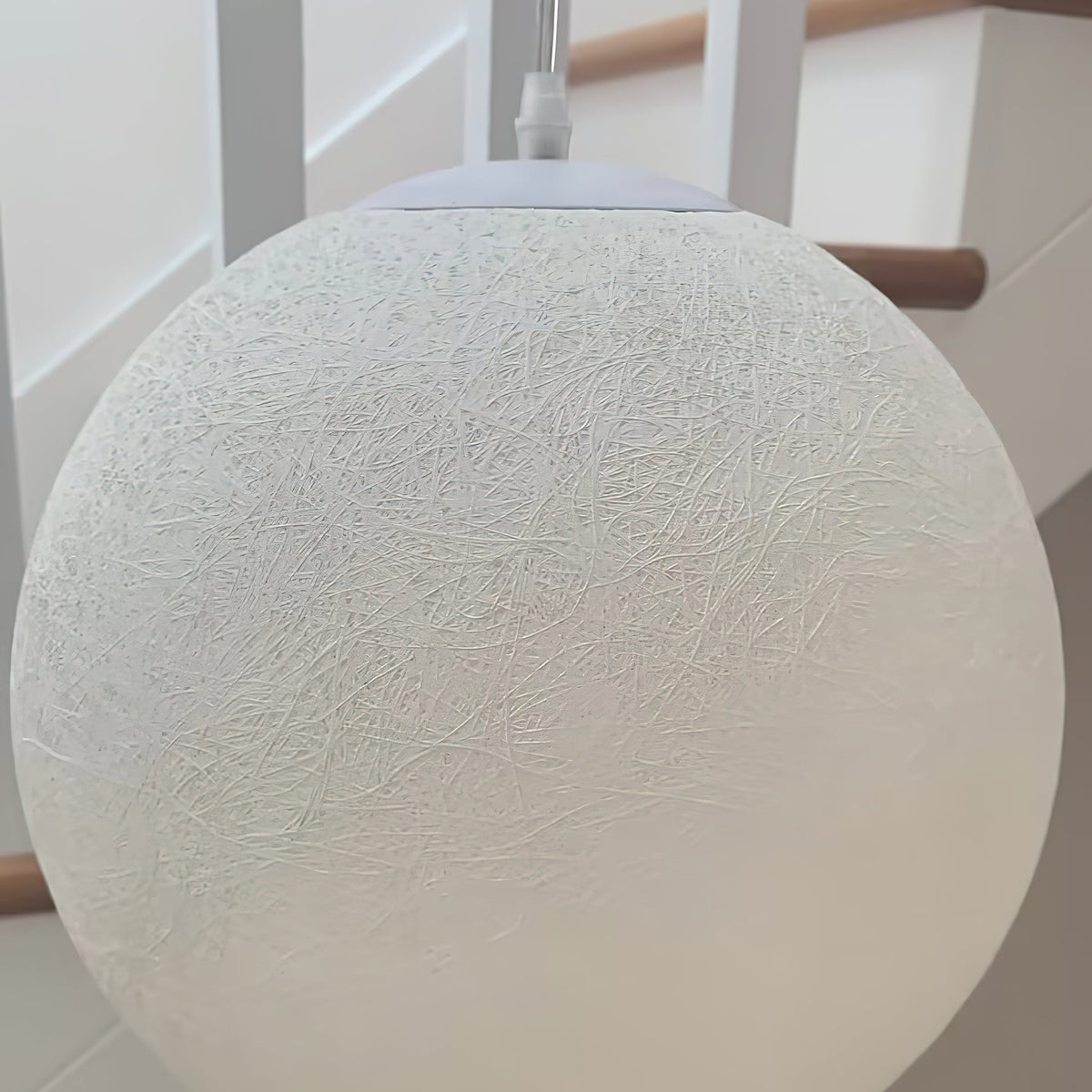 Close view of the fine, web-like fibre texture on a large white Clérachic sphere, with the white canopy and cord at the top.