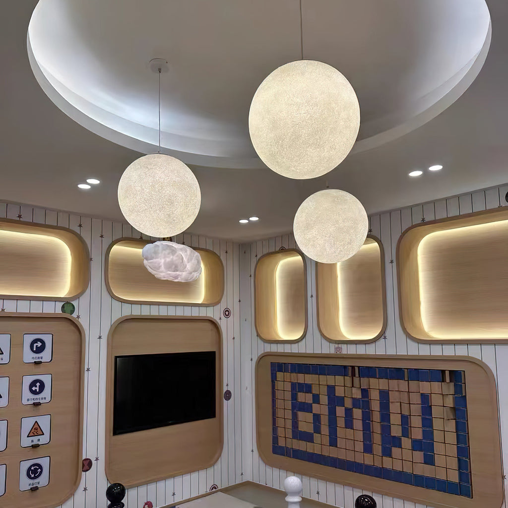 Three lit Clérachic spheres of different sizes hang under a round, domed ceiling with spotlights, over a wall of padded wood panels.
