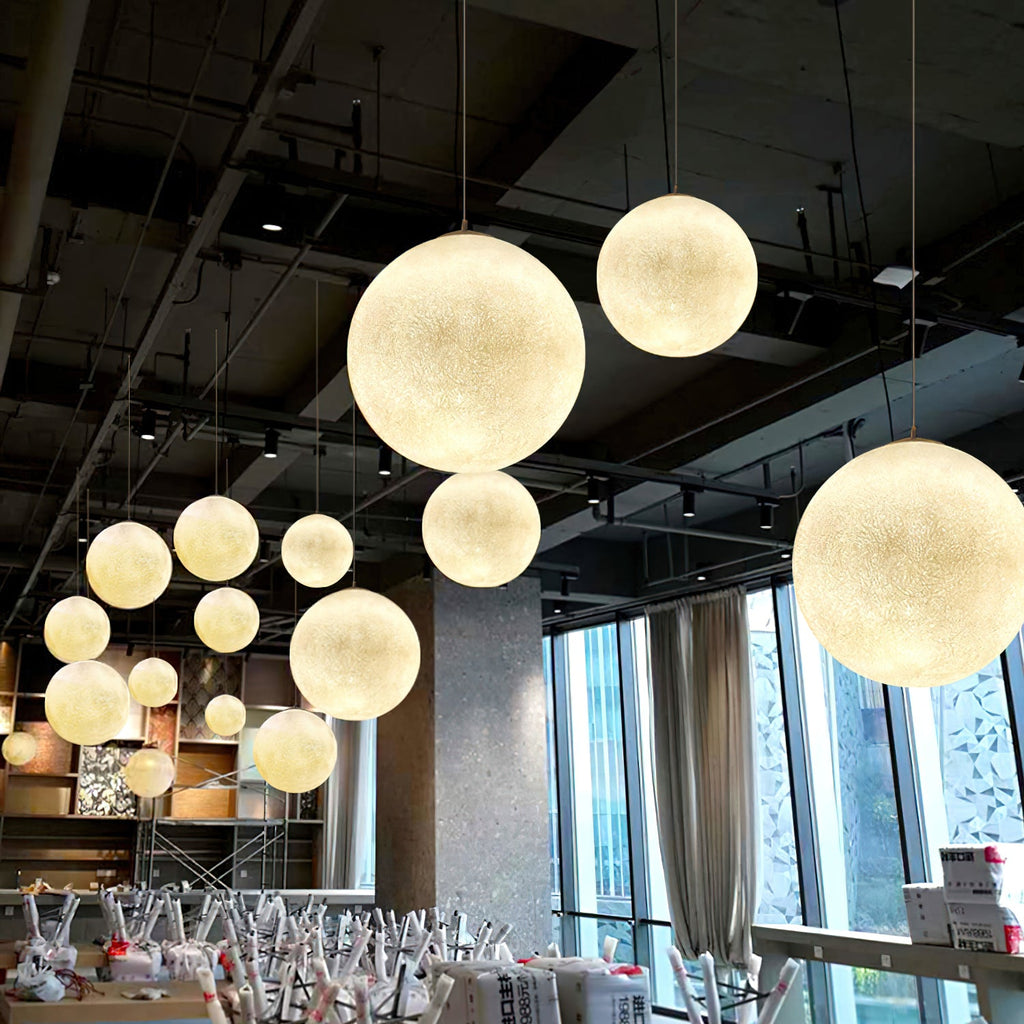 Warm-lit Clérachic spheres of several sizes hang beneath a dark industrial ceiling, with floor-to-ceiling windows behind them.