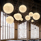 Clérachic spheres in cream and gold hang at staggered heights before tall windows with a decorative timber screen.