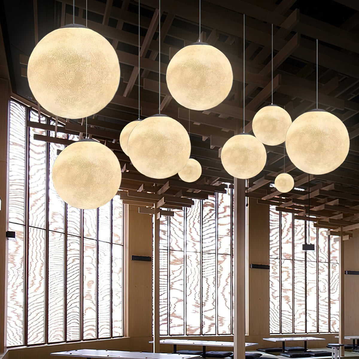 Clérachic spheres in cream and gold hang at staggered heights before tall windows with a decorative timber screen.