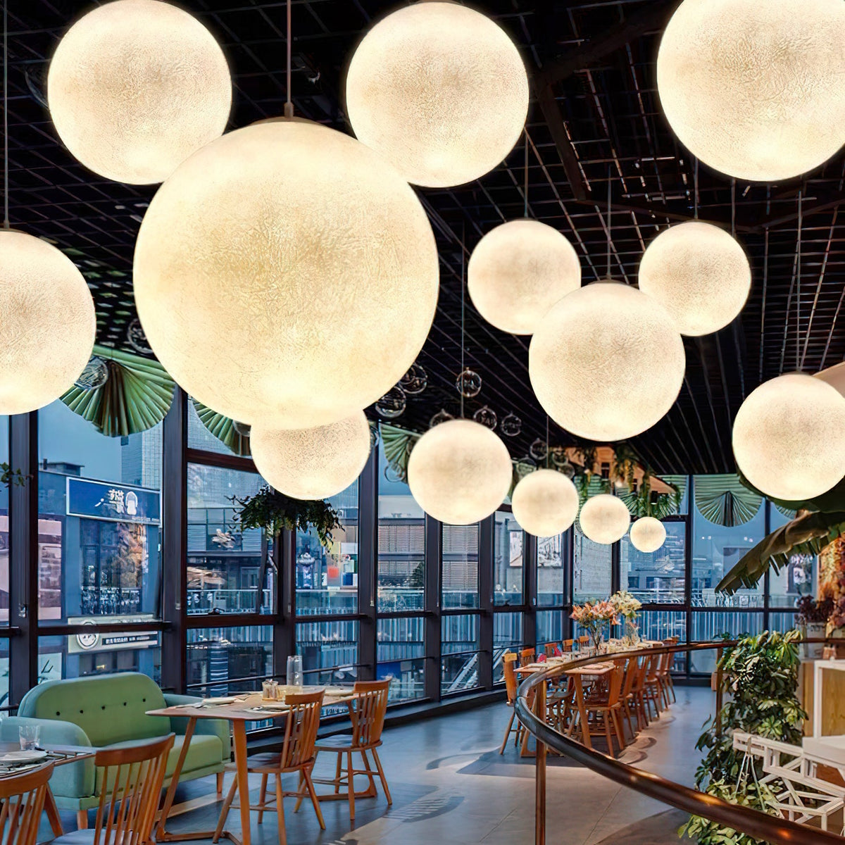 A dense cluster of Clérachic spheres in many sizes hangs under a black ceiling in a glass-walled restaurant.