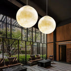 Two large Clérachic spheres with a creamy yellow tint hang in a lobby with floor-to-ceiling glass and wood panelling.