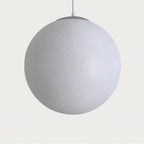 Unlit white Clérachic sphere with a finely speckled shell and a grey canopy, hung from a thin cord on a soft grey backdrop.