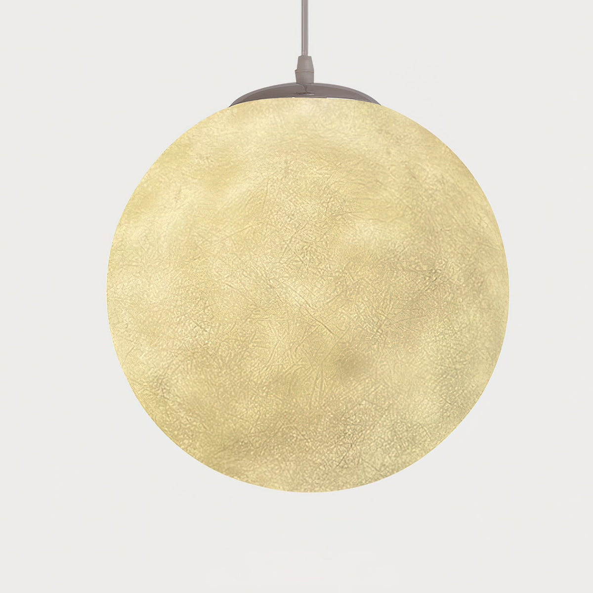 Lit Clérachic sphere glowing warm yellow, its crater-like surface visible, hung from a grey canopy against a pale backdrop.