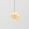 The smallest Clérachic sphere pendant, lit warm cream on a thin cord, against a light grey backdrop.