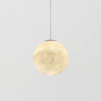 A small Clérachic sphere pendant glows warm cream on a slim white cord, centred against a light grey backdrop.