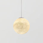 A mid-small Clérachic sphere pendant, lit, with a grey canopy and a fine cord, set against a plain light grey backdrop.