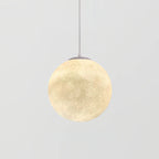 Mid-size Clérachic sphere pendant glowing warm cream, with a grey canopy and thin cord, against a plain light grey backdrop.
