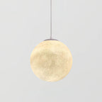 A larger Clérachic sphere pendant, lit, showing the crater-like texture and a grey canopy on a pale grey background.