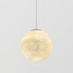 A large lit Clérachic sphere pendant with a pale crater texture and grey canopy, framed against a light grey backdrop.