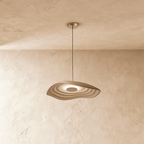 Clérachic rippling resin pendant in warm taupe, lit from within, hung on a slim cord against a plaster ceiling and wall