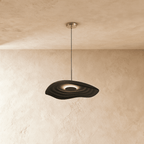 Clérachic rippled resin pendant in deep charcoal with a glowing centre, on a slim rod and cord by a plaster wall