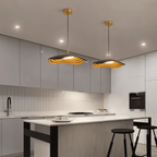Pair of Clérachic wavy black resin pendants with warm amber ripples inside, hung over a modern kitchen island
