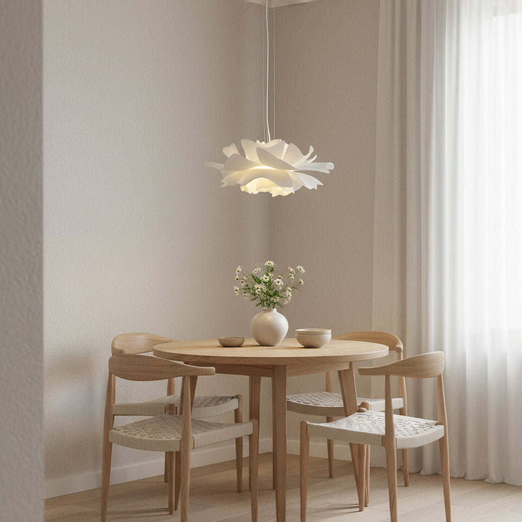 Clérachic white petal pendant above a small round oak table with woven-seat chairs, against a pale wall and a long curtain.