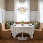 Clérachic white petal pendant above a round white-clothed table in a breakfast nook with a wooden bench.