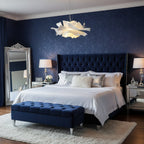 Clérachic white petal pendant above a bed with a navy tufted headboard, a navy bench and a tall silver-framed mirror.