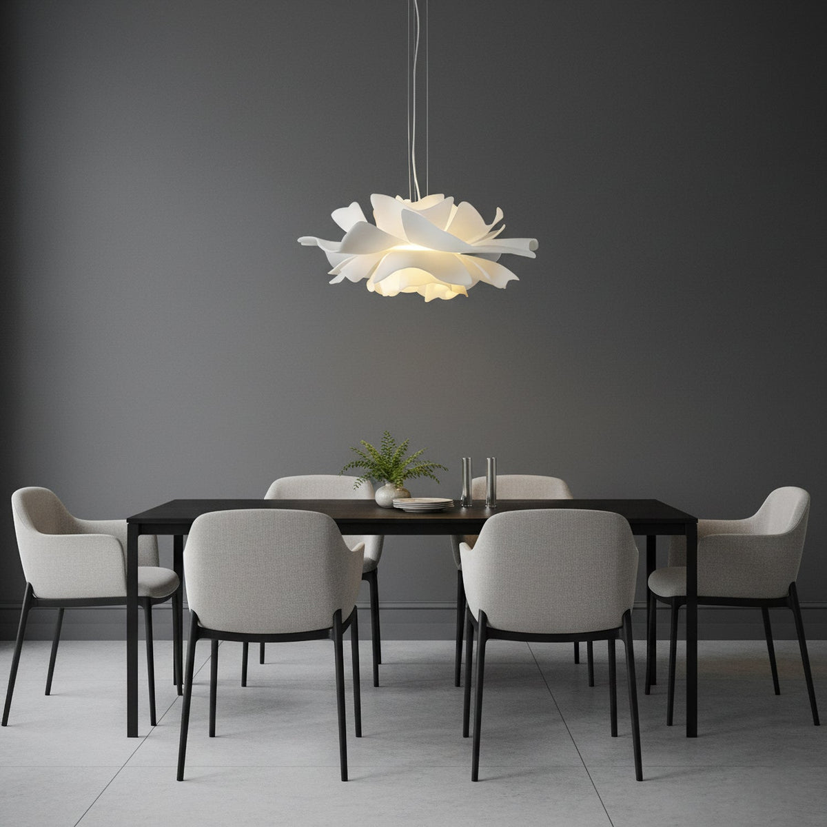 Clérachic white petal pendant against a dark grey wall, above a black dining table with grey chairs.
