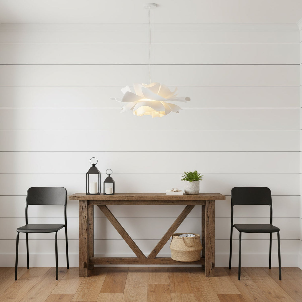 Clérachic white petal pendant against white wall boards, above a rustic console table with two black chairs and lanterns.