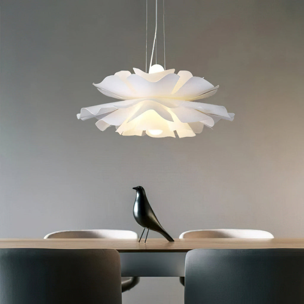 Clérachic white petal pendant with layered ruffled petals above a table with a black bird figure, against a grey wall.