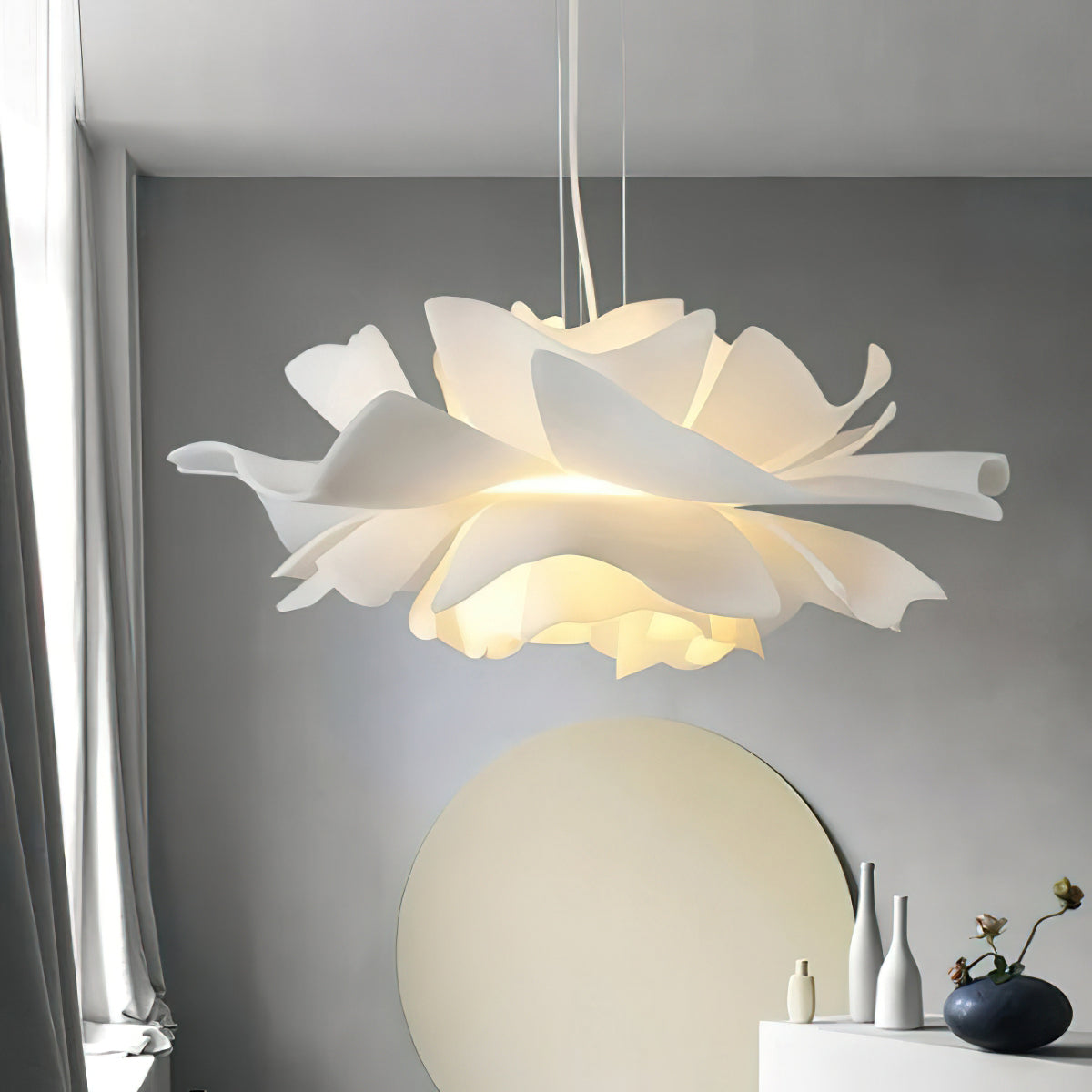 Close view of the layered petals on this lit Clérachic pendant, with a round pale mirror and vases below.