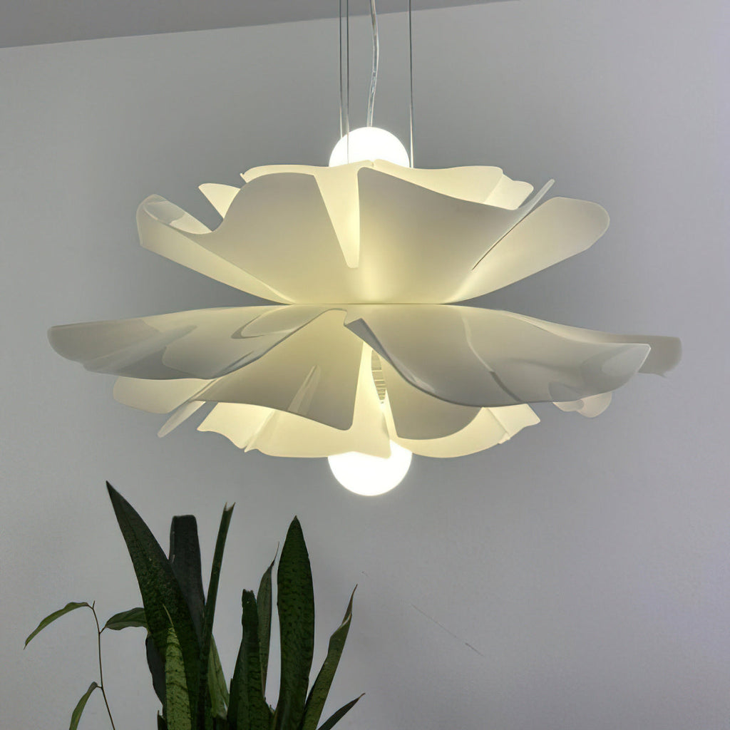 Close view of a Clérachic white petal pendant with its bulb visible above and below the layers, in front of a plant.