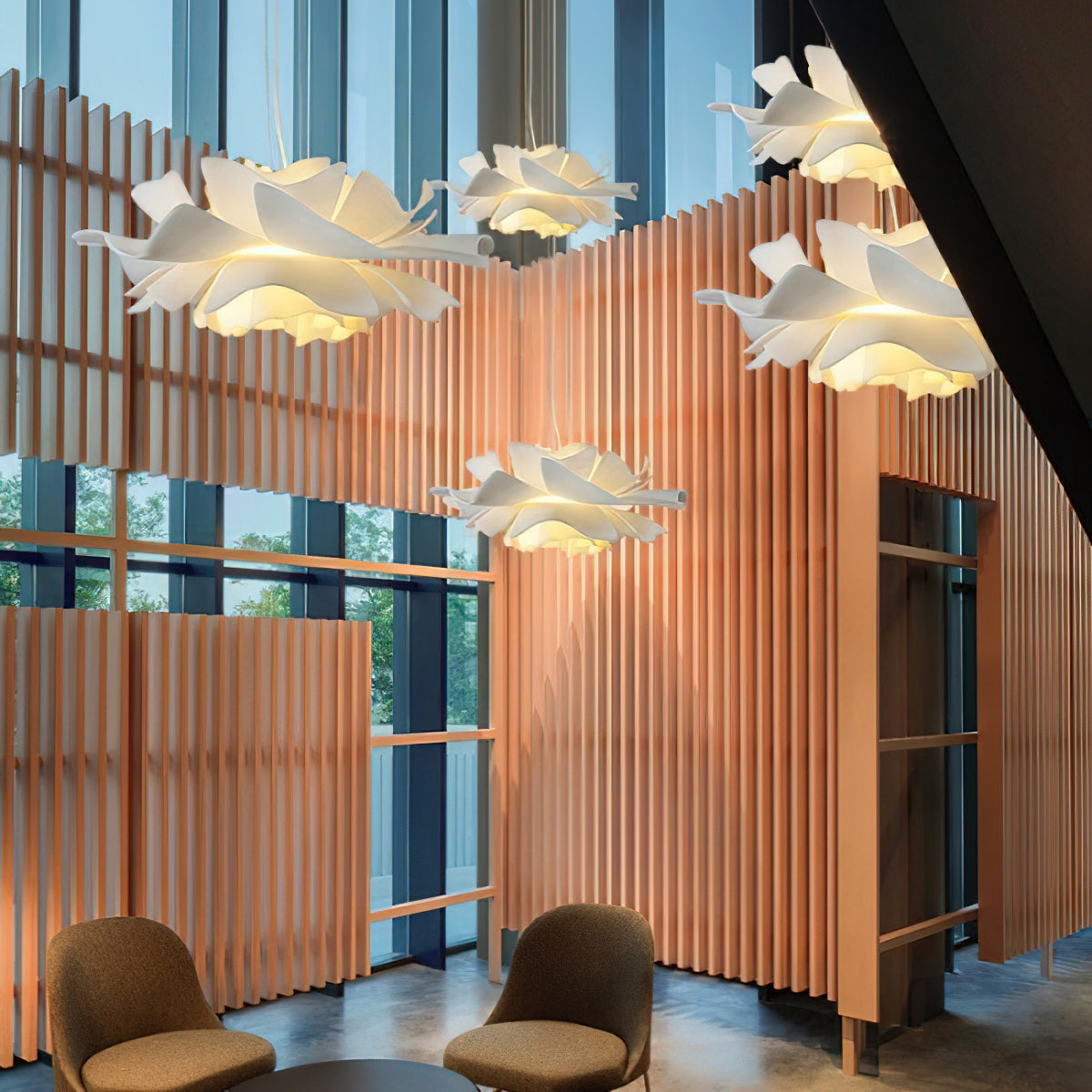 Several Clérachic white petal pendants hung at different heights between warm timber slats in a tall, glazed room.
