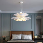 Clérachic white petal pendant on a ceiling canopy above a bed with a tan headboard, in a blue-grey panelled bedroom.
