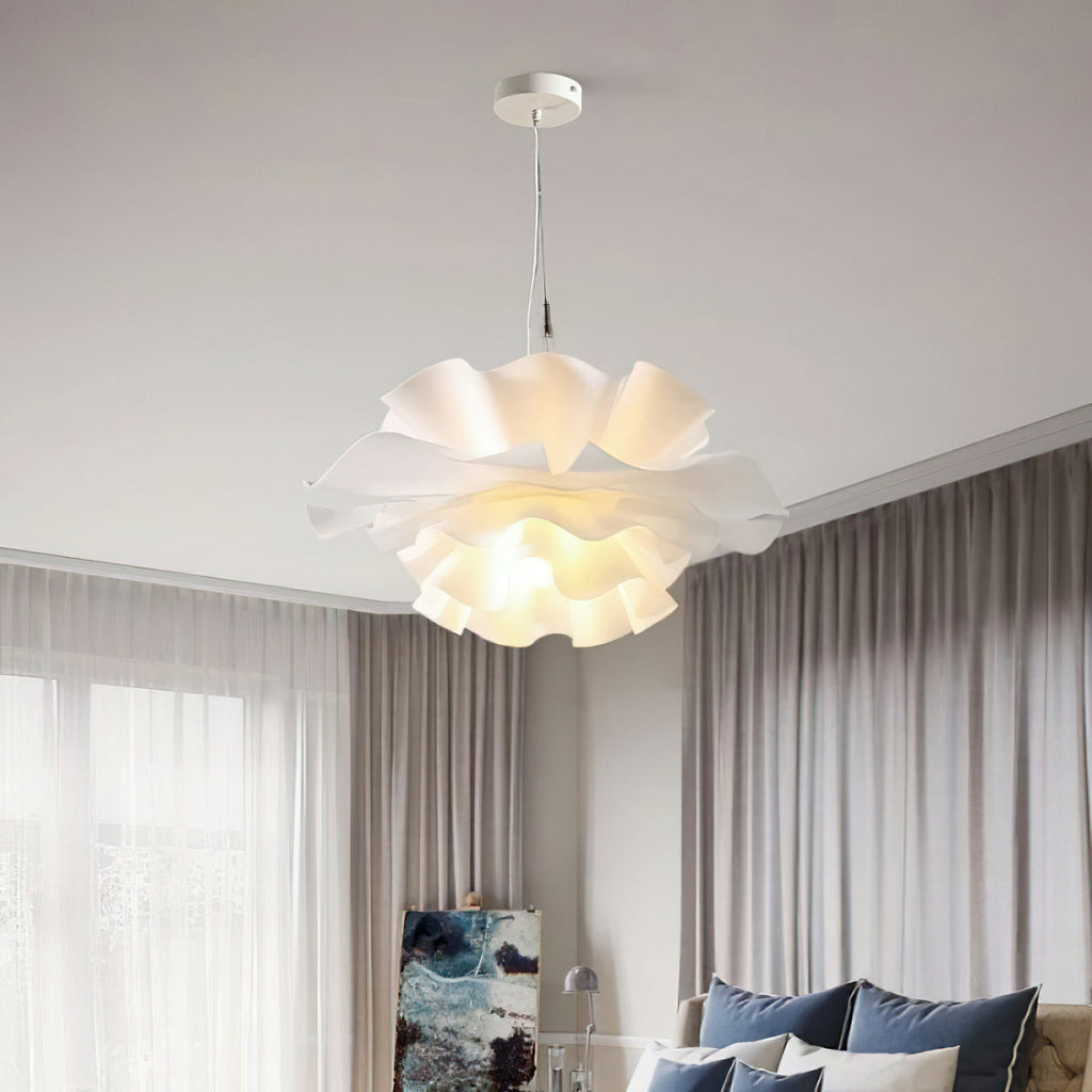 Clérachic white petal pendant on a white canopy, above a sofa with blue cushions in a room with long grey curtains.