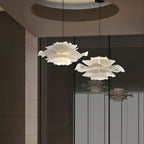 Two Clérachic white petal pendants of different sizes against a tiled wall and glass panel, with a round ceiling recess above.