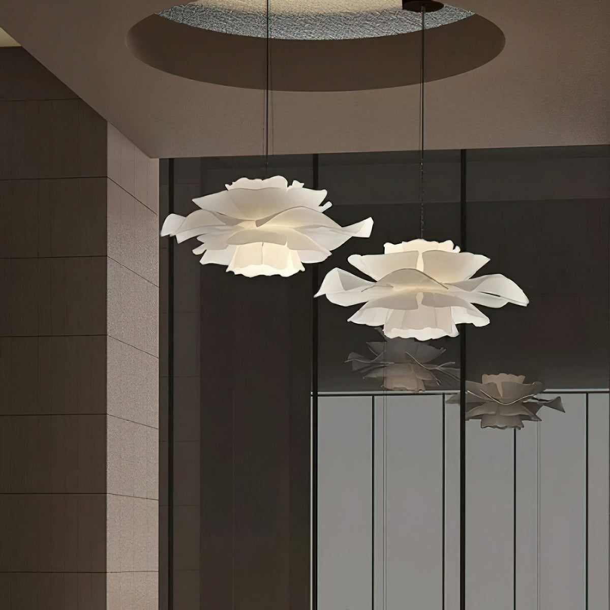 Two Clérachic white petal pendants of different sizes against a tiled wall and glass panel, with a round ceiling recess above.