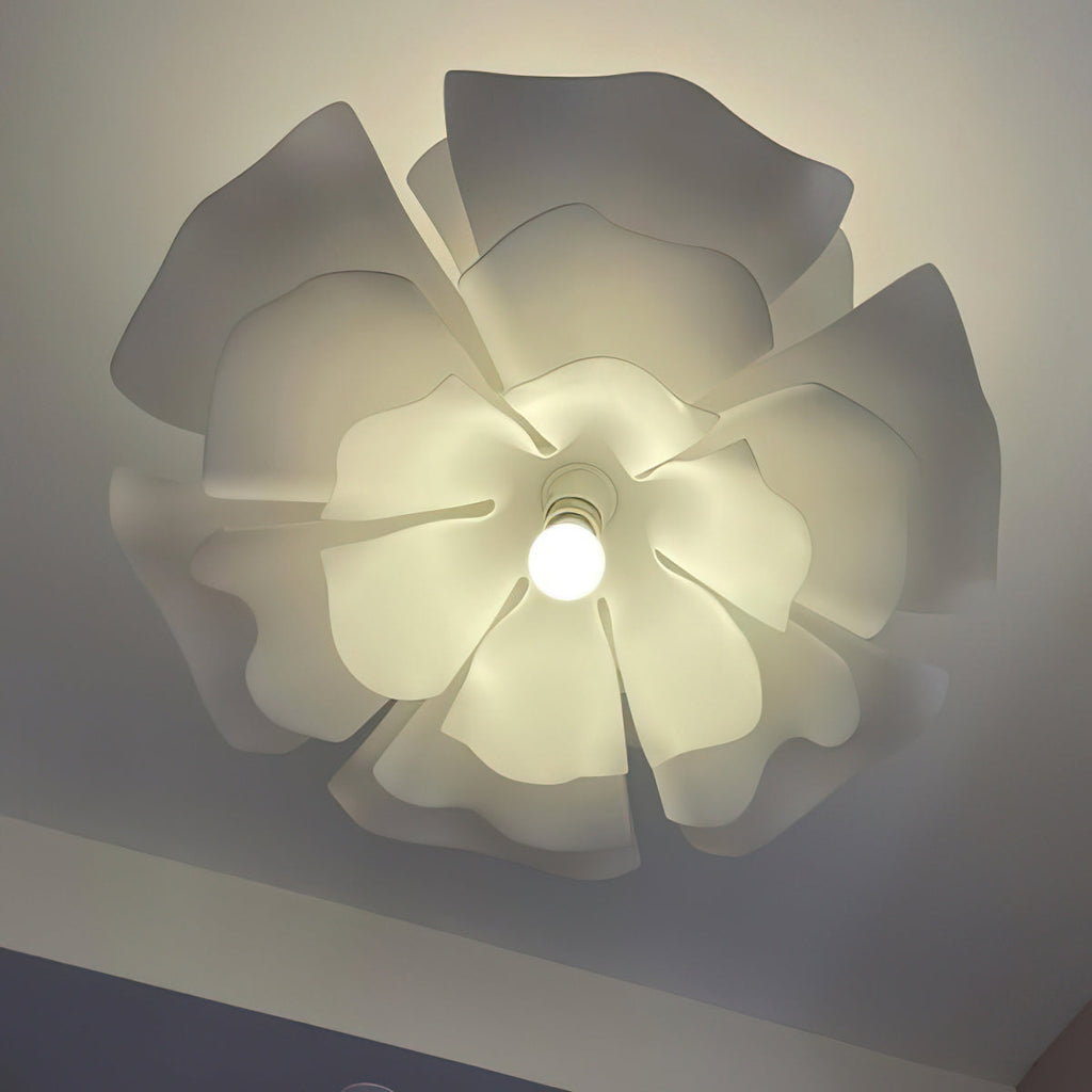 Close view from below of the overlapping petals of this lit Clérachic pendant, with a round bulb at the centre.
