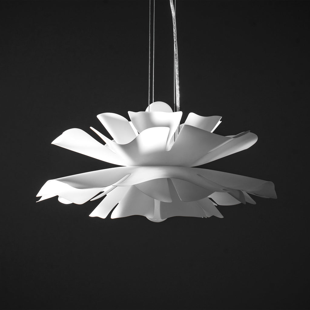Unlit Clérachic white petal pendant with layered, notched petals, hung on a thin cable against a black backdrop.