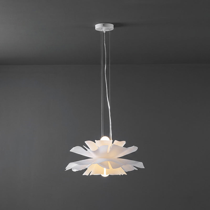 Clérachic white petal pendant lit, hung from a white canopy by thin cables, against a dark grey wall.