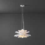 Clérachic white petal pendant lit, hung from a white canopy by thin cables, against a dark grey wall.