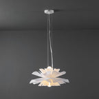 Clérachic white petal pendant on slim cables from a white canopy, with a bulb glowing inside, on a dark grey wall.