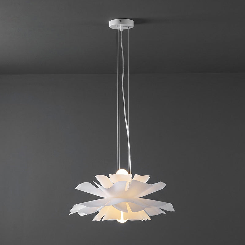 Small Clérachic white petal pendant lit and hung from a ceiling canopy, on a dark grey wall.