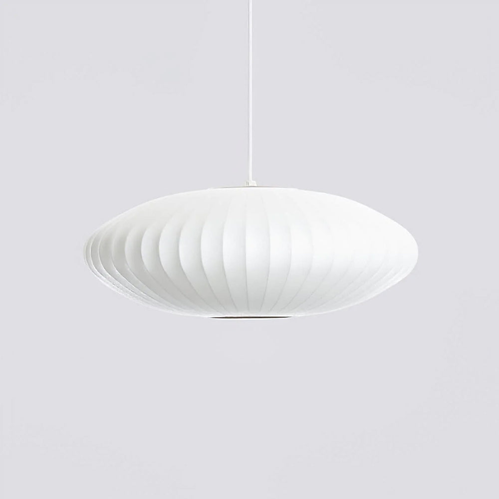 On pale grey, a wide white Clérachic pendant hangs from a thin cord, its ribbed shade glowing softly at the edges.