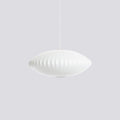 On a pale grey backdrop, a small, flat white Clérachic pendant hangs from a thin cord, its ribs fading softly.