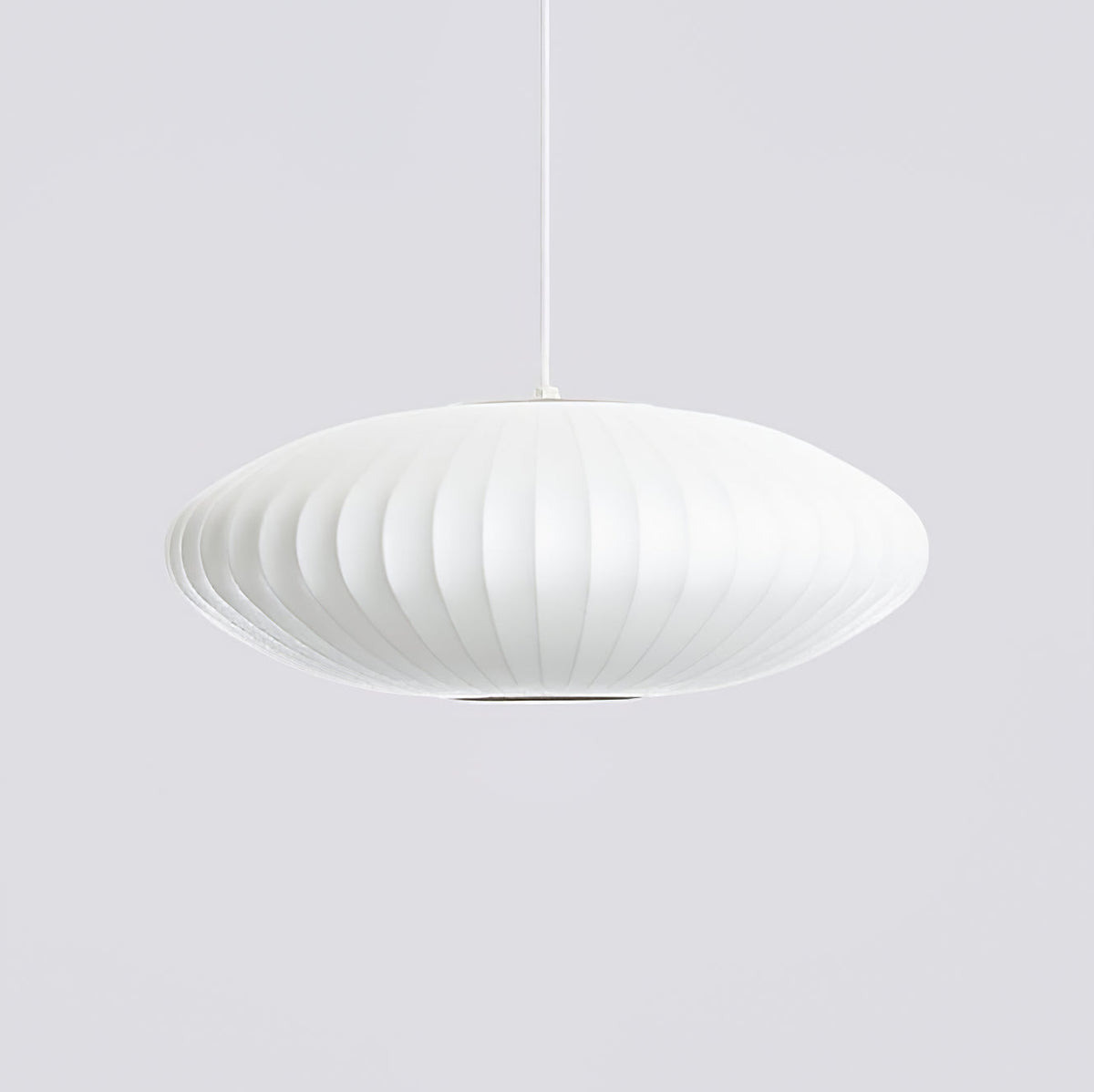 A wide, flat Clérachic pendant with a white ribbed shade hangs on a pale grey backdrop, its lower rim showing a darker opening.