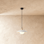 Clérachic pendant light in white, the saucer shade and opal glass diffuser glowing below a plaster ceiling.