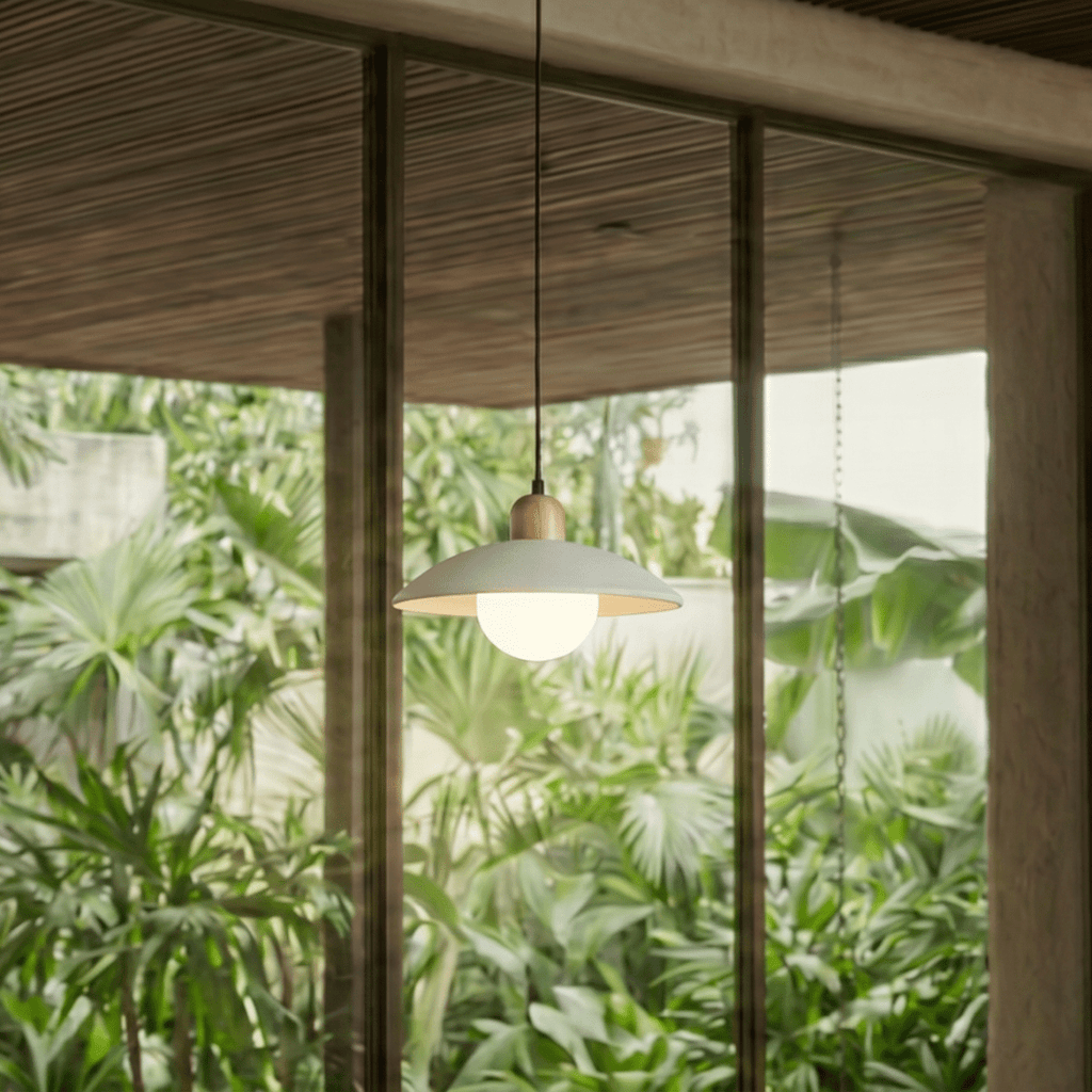Clérachic white pendant light glowing beside floor-to-ceiling windows overlooking dense tropical greenery.