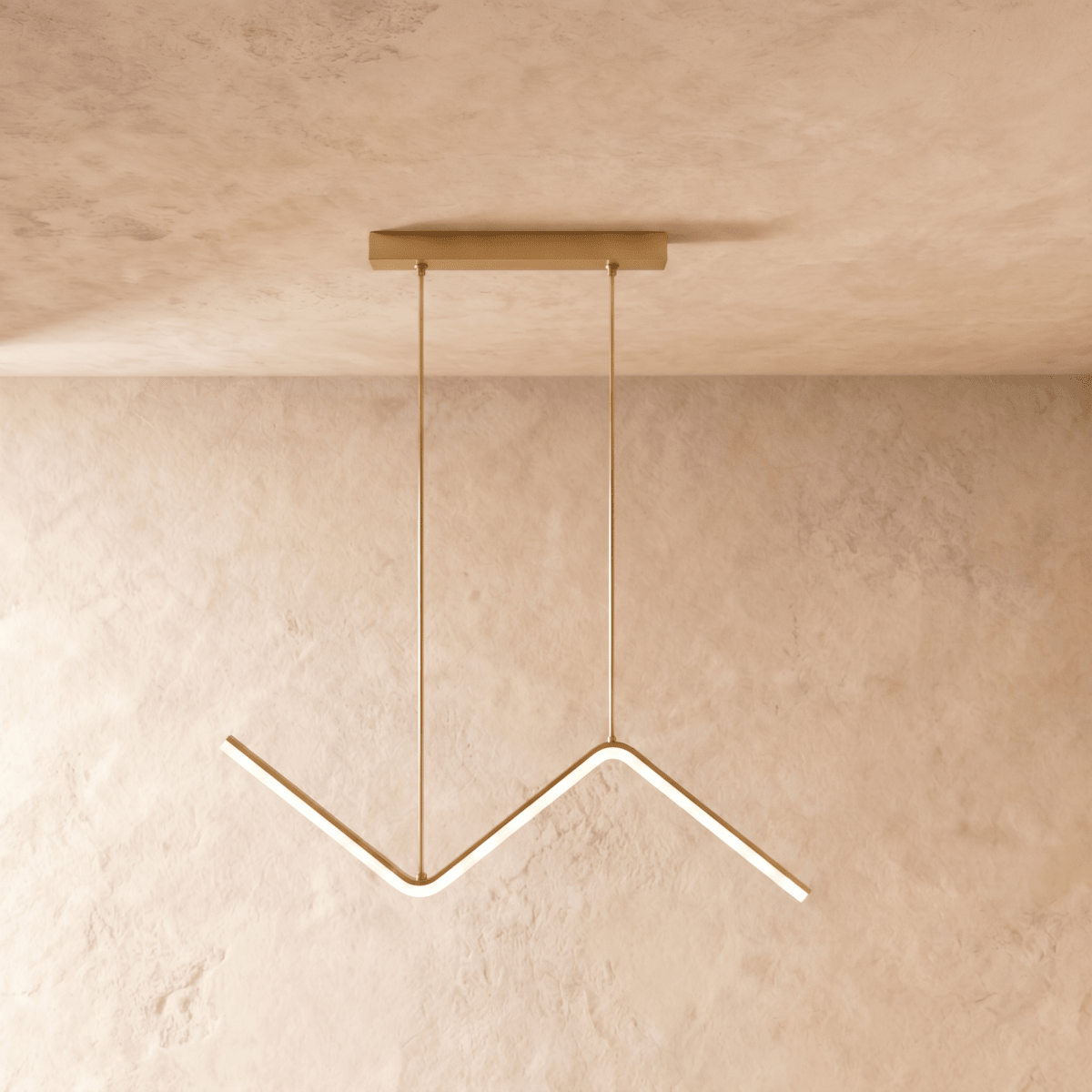 Clérachic gold zig-zag LED pendant with a single bar and matching gold cables and canopy, on a plaster wall.