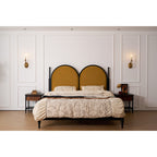Clérachic sconces flank a panelled wall above a mustard headboard and cream bedding, both candle bulbs lit.