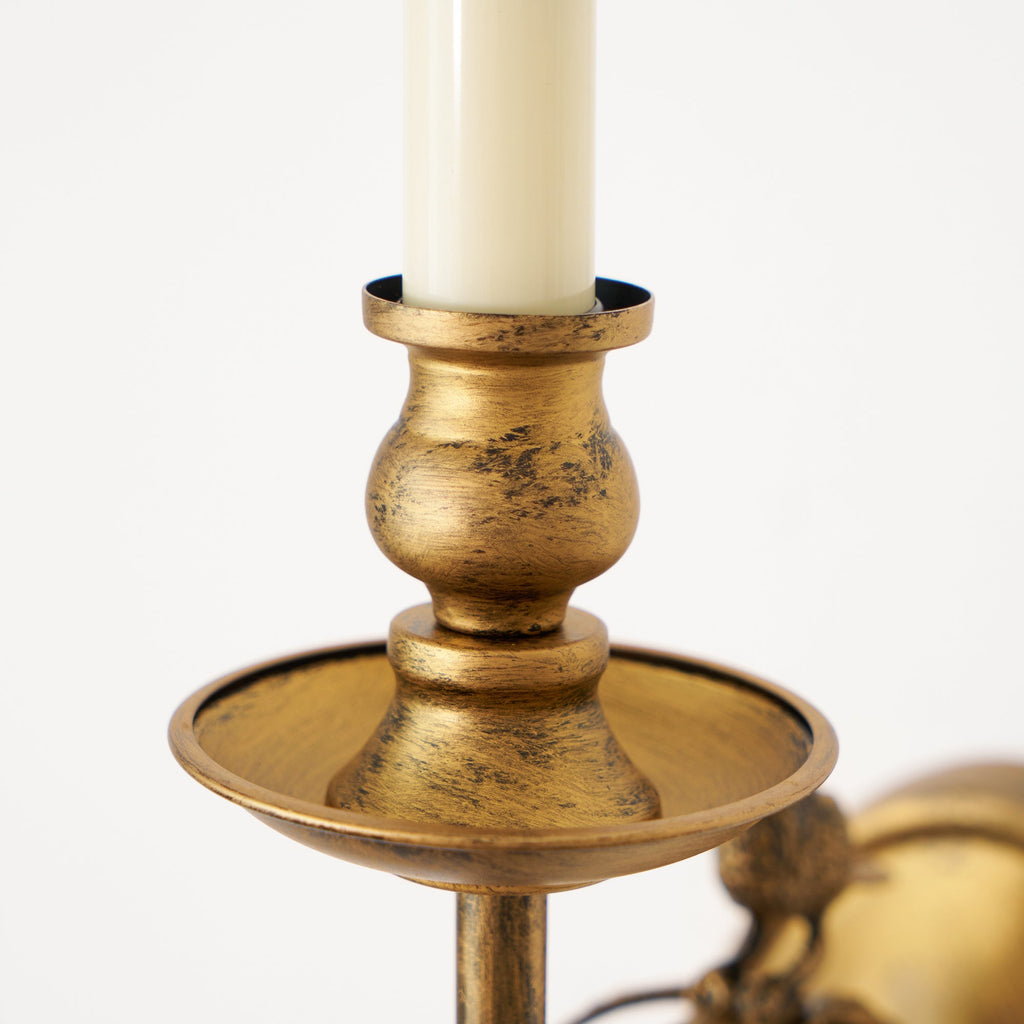 A close-up of the Clérachic sconce's candle-style holder, showing the distressed antique brass finish in detail.