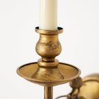 A close-up of the Clérachic sconce's candle-style holder, showing the distressed antique brass finish in detail.