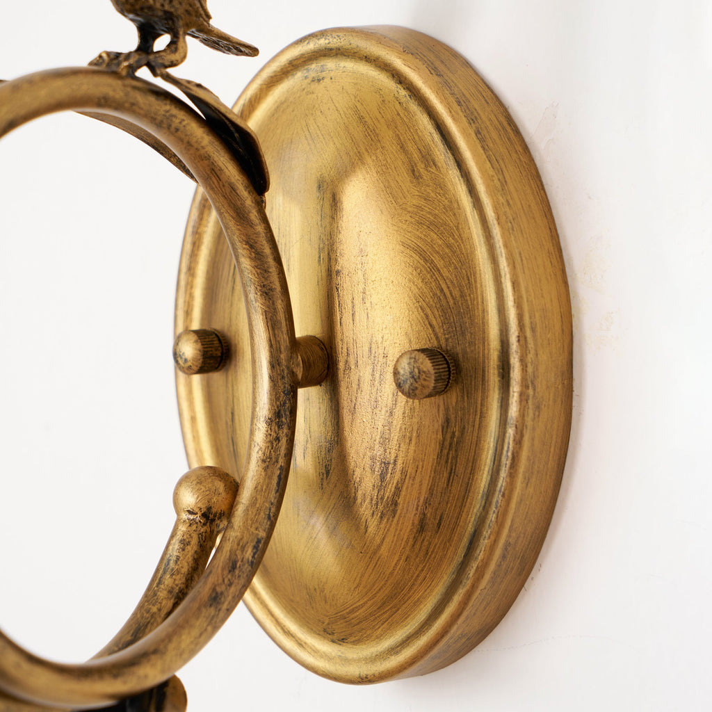 The Clérachic sconce's ring and circular backplate shown close-up, revealing the brushed brass finish and mounting studs.