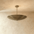 Clérachic perforated disc pendant light in vintage brass, hung from a plaster ceiling and photographed in studio.