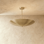 Clérachic perforated disc pendant light in polished brass, hung from a plaster ceiling and photographed in studio.