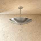 Clérachic perforated disc pendant light in chrome, hung from a plaster ceiling and photographed in studio.